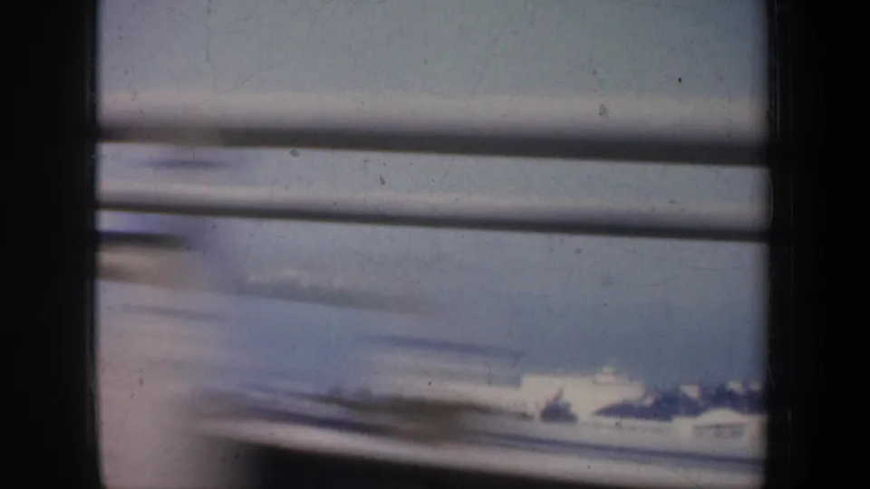 1957 San Francisco side-window view showing bridge railing, dark interior pillar and a soft distant shoreline or water surface.