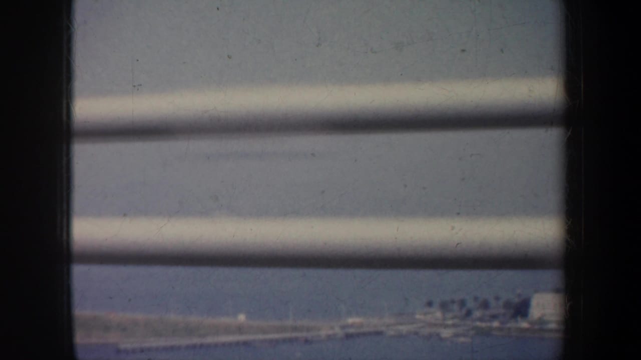 Distant shoreline and blue water partly obscured by horizontal slats.