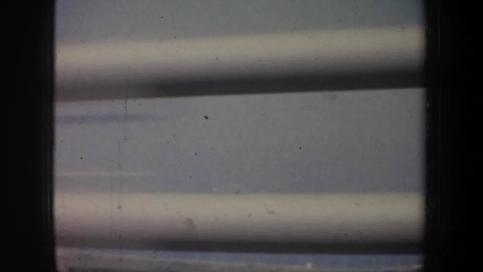 San Francisco coastal water seen through slats in a faded 1957 8mm frame, with no people or readable markings visible.