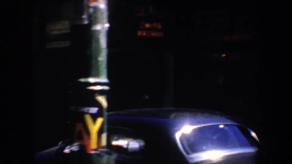 1957 San Francisco night frame showing the Chinese crockery sign, a street pole, and a classic car in low light.