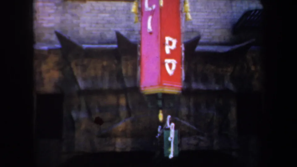 1957 San Francisco 8mm frame showing a red vertical sign with white lettering above a dim brick alley entrance.