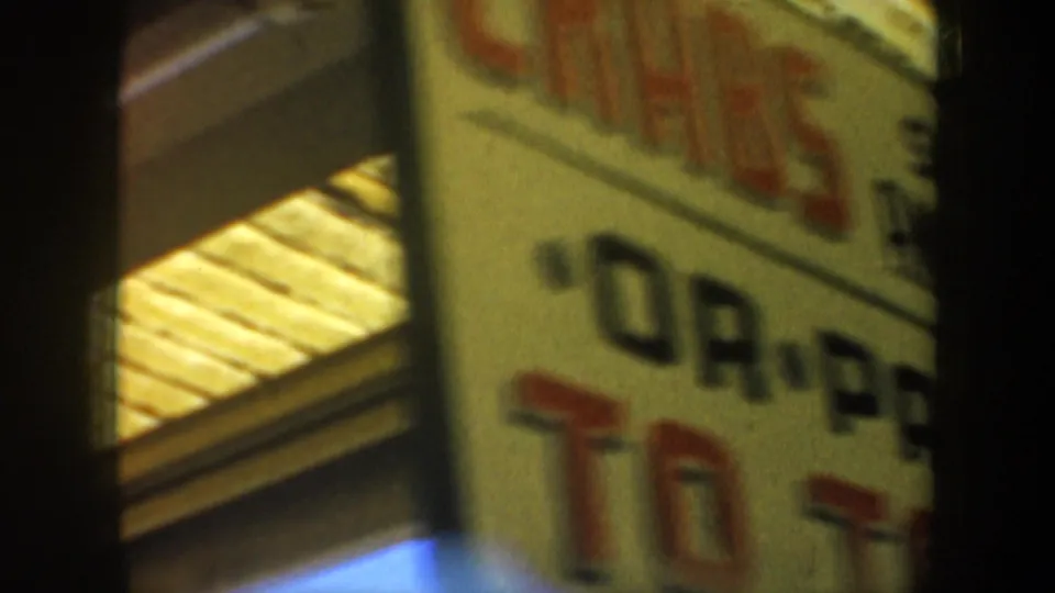 A blurred partial storefront sign appears in the 1957 San Francisco home-movie footage, with lettering not fully readable.
