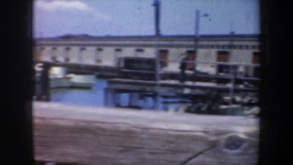 Soft final frame of a San Francisco pier-side building, walkway, posts, and blue sky in 8mm home-movie footage.