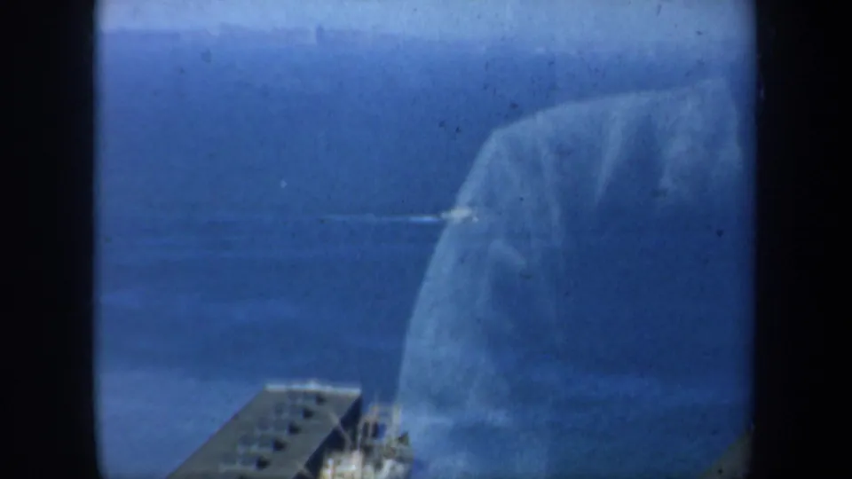 Obstructed 8mm view of San Francisco waterfront water with a small pier or platform and soft blue exposure.