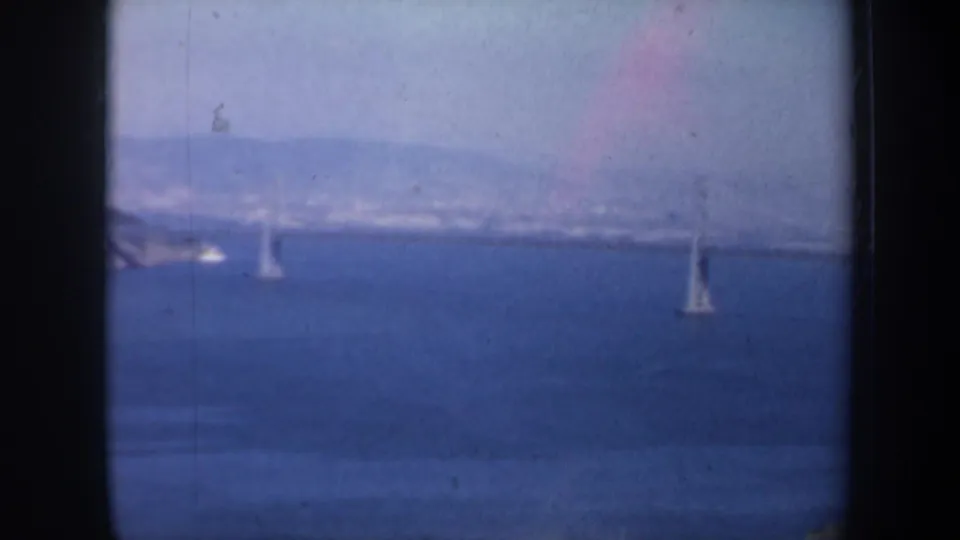 San Francisco Bay appears in a soft 1957 8mm view with distant bridge elements, shoreline hills, and visible film wear.