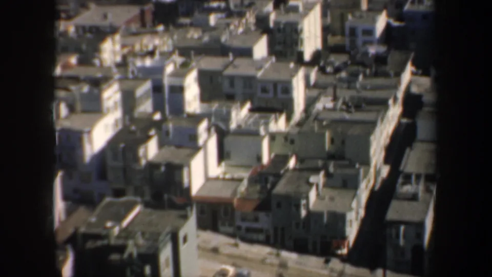 San Francisco hillside housing appears tightly packed in this 1957 8mm frame, with rooftops, streets, and bright sunlit facades.