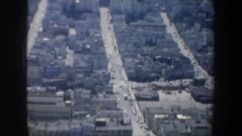 1957 San Francisco overhead view showing compact rooftops, broad streets, and cars within visible 8mm frame borders.