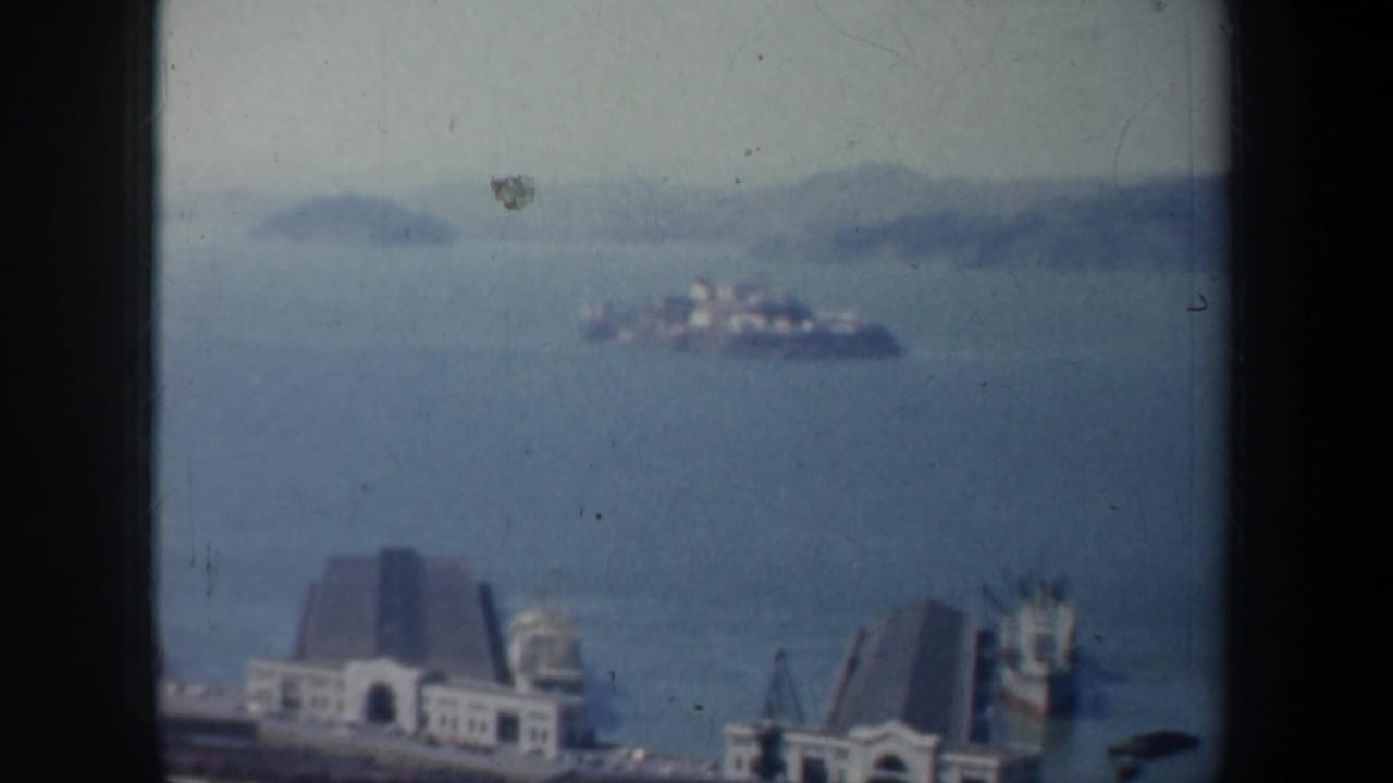 Distant San Francisco Bay view with waterfront buildings, piers, islands, and blue water.