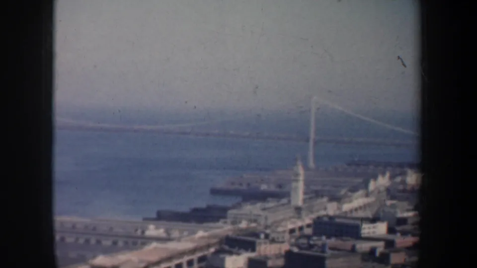 Late in the 1957 pan, the Bay Bridge tower, open bay, piers, and waterfront buildings fill the distant view.