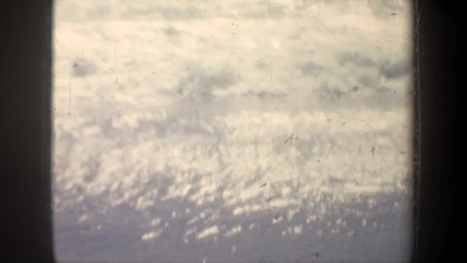 Bright, grainy 8mm view of foaming shoreline water under a San Francisco pier, with heavy sun reflection.