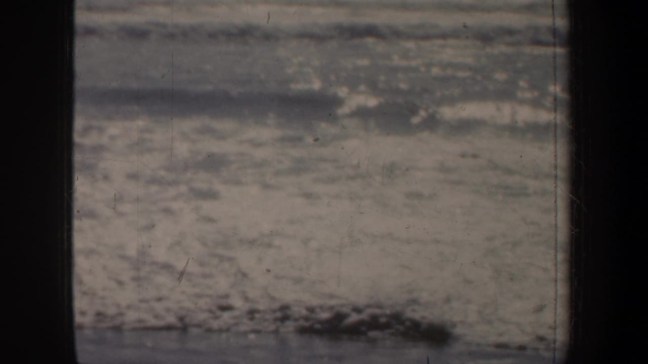 Muted surf and textured water fill the frame, with a dark 8mm border at the edge.