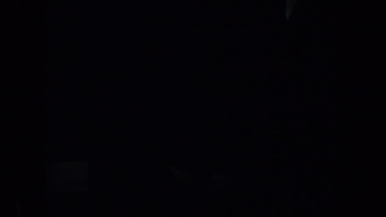 A nearly black 1957 San Francisco 8mm frame with only faint rectangular light patches and unreadable shadowed forms visible.