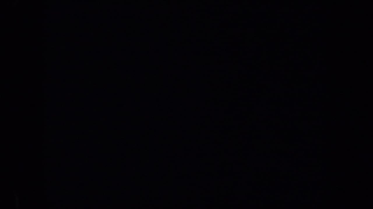 Very dark frame with only faint color and shadow detail visible.