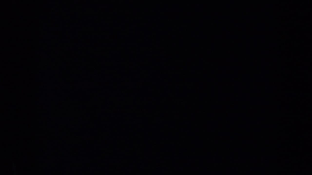 Very dark frame with indistinct shadowed shapes and little readable detail.