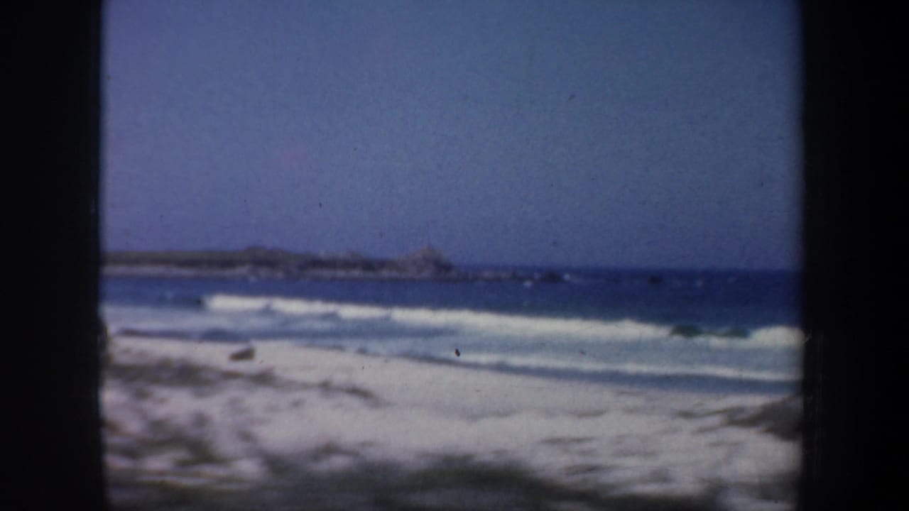 Coastal beach and waves seen through dark film-frame borders.