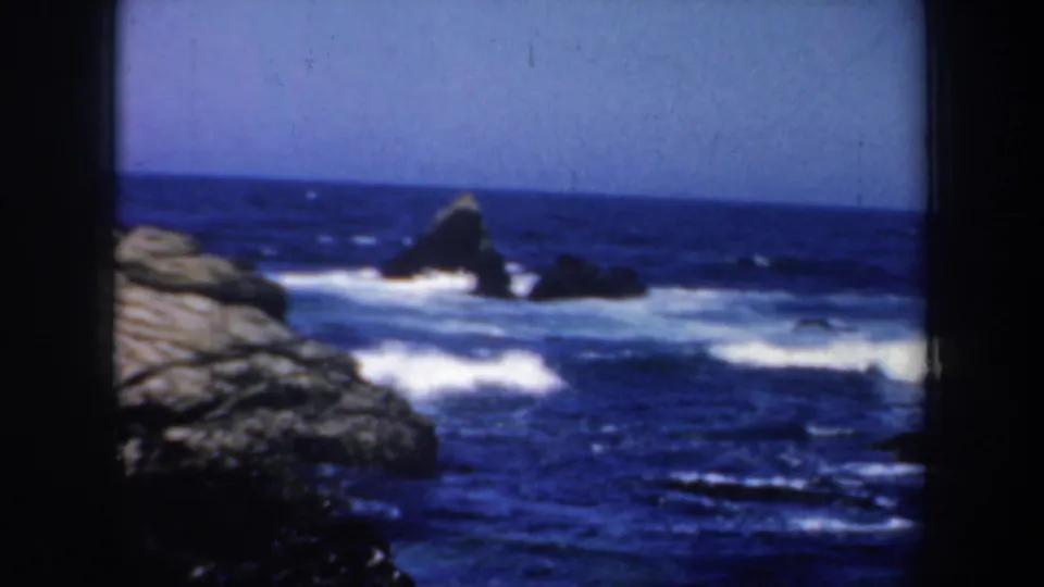 1957 San Francisco-area coastal view with a pointed sea stack, foaming surf, open water, and rocks along the lower frame.