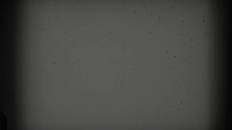 Underexposed 1959 8mm frame from the Barcelona clip, with no clear subject beyond grain, dust, and film-edge shadow.