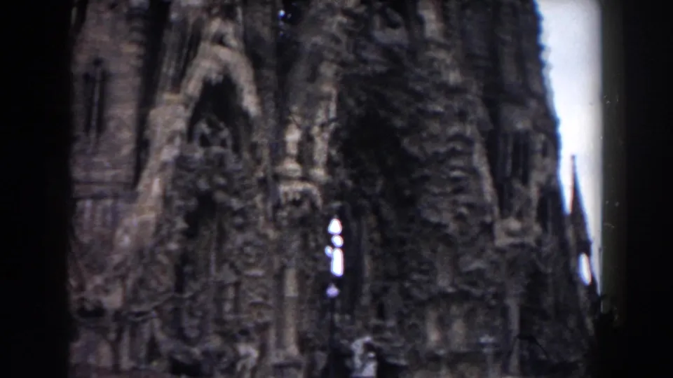 1959 Barcelona 8mm frame showing Sagrada Familia facade details, including carved stone surfaces, pointed arches, and dark frame edges.