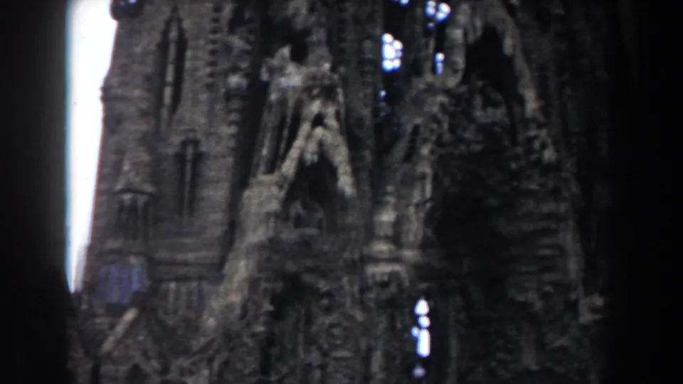 1959 Barcelona 8mm frame showing a close portion of Sagrada Familia, with vertical stonework, pointed openings, and dark edge vignetting.