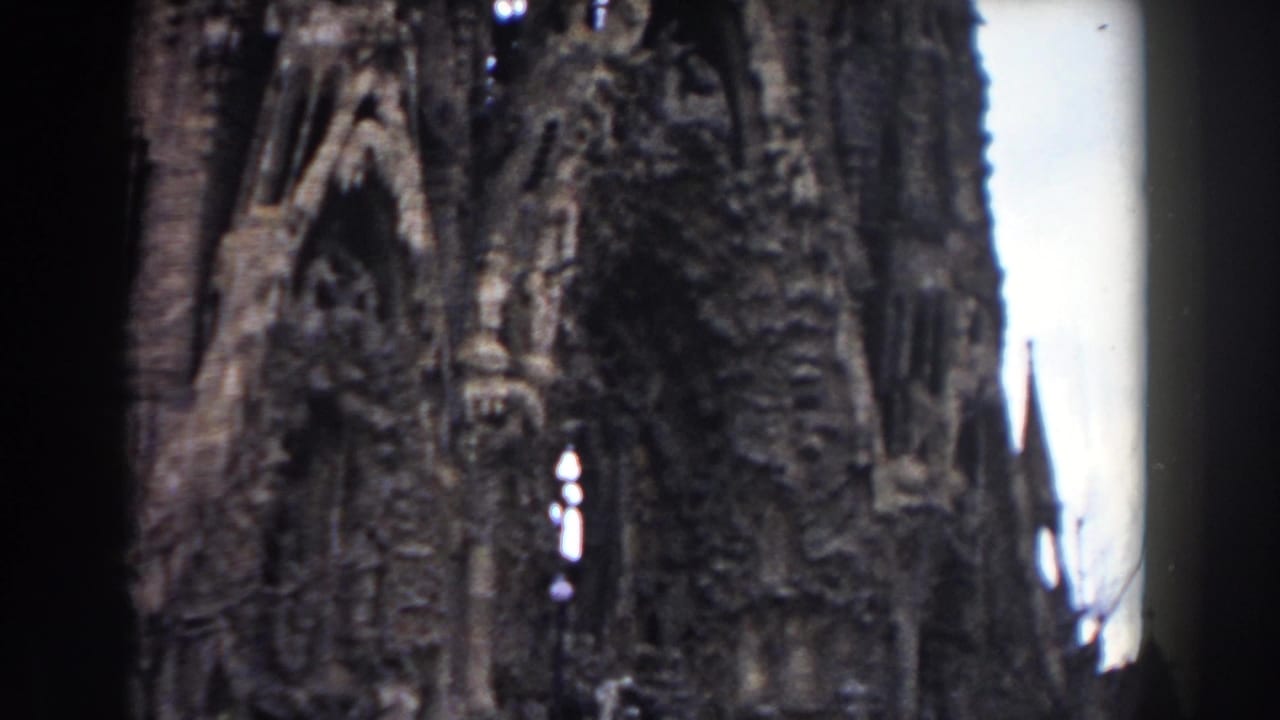 1959 Barcelona 8mm frame showing an ornate stone facade with pointed arches, sculptural carving, and bright sky behind the structure.