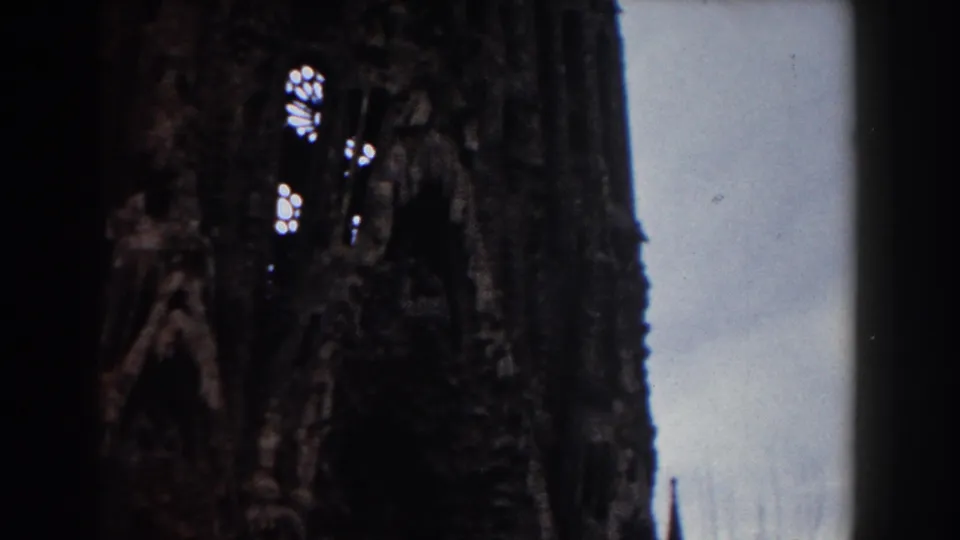 1959 Barcelona 8mm frame showing a darker section of ornate stone architecture, with arched recesses and pale sky along the building edge.