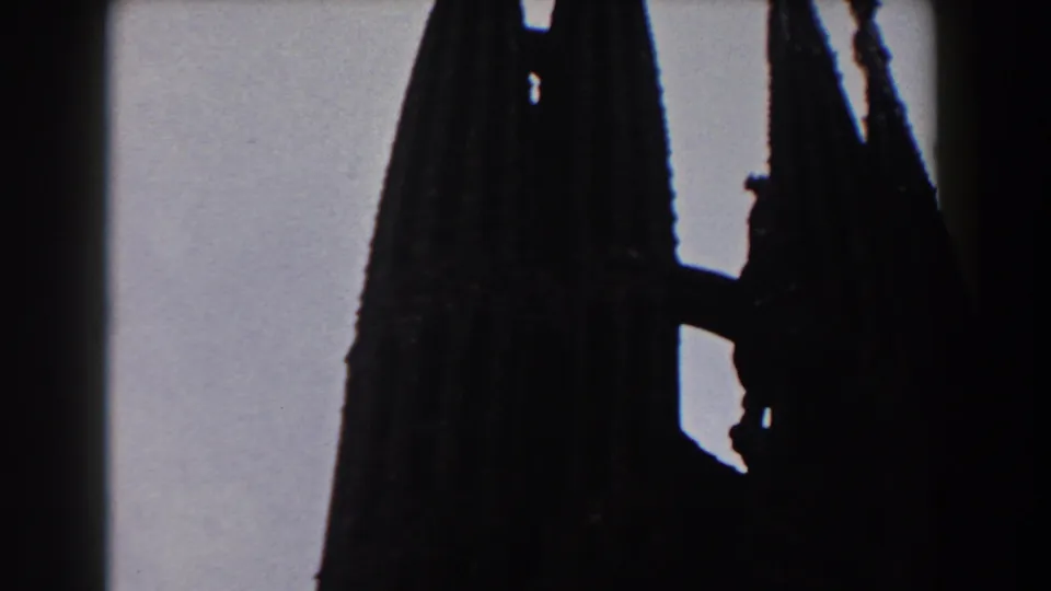 Final 1959 Barcelona 8mm frame showing a dark Gothic church spire and facade edge, with faint window detail visible.