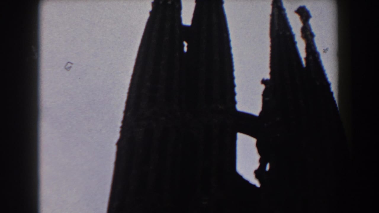 Silhouetted church spires against a pale sky with dark film edges.