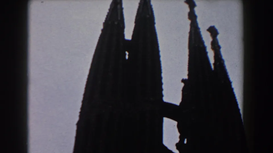 1959 Barcelona frame with clustered Gothic-style spires, small finials, and a dark connecting architectural section.