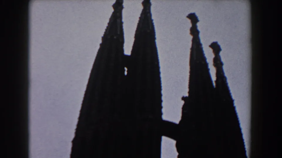 1959 Barcelona 8mm frame showing tall silhouetted church spires from a low visitor perspective, with visible film borders.