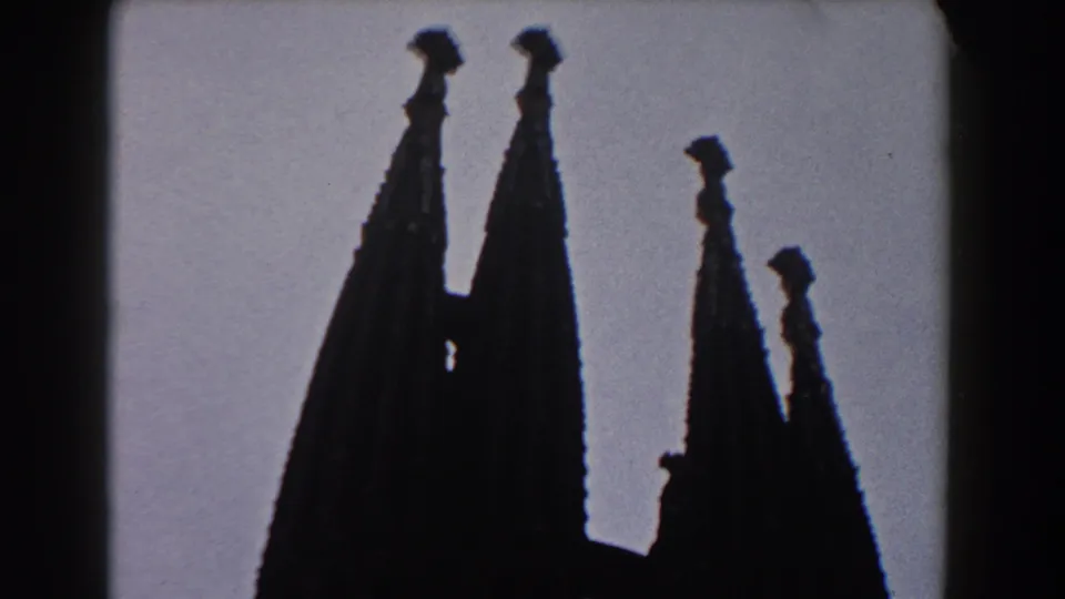 1959 Barcelona frame with multiple church spires separated against the sky, seen in dark silhouette on 8mm film.
