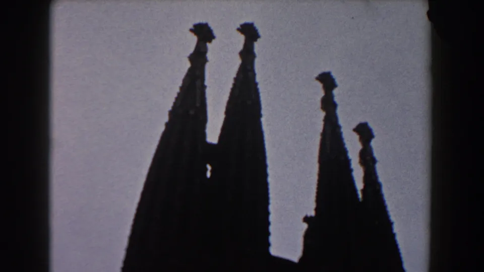 1959 Barcelona 8mm frame showing dark, ornate church spires silhouetted against a pale sky.