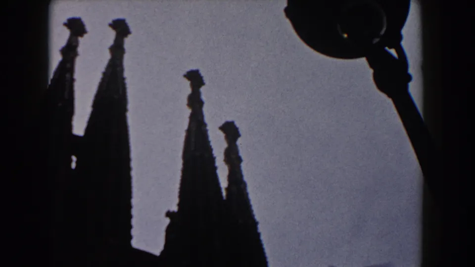 1959 Barcelona 8mm frame showing silhouetted Gothic cathedral spires against a pale sky.