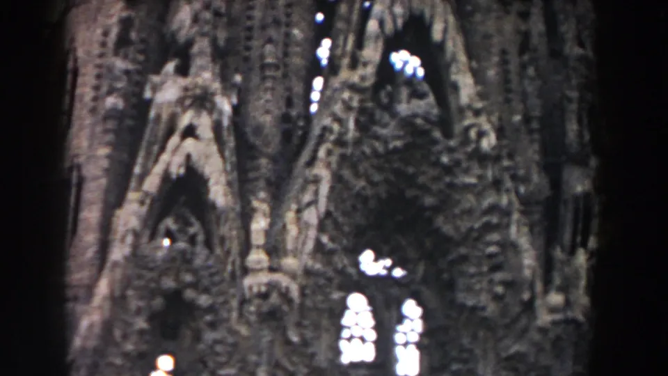 Barcelona 1959 home-movie still showing the cathedral facade from close range, with tall carved arches and overexposed window openings.