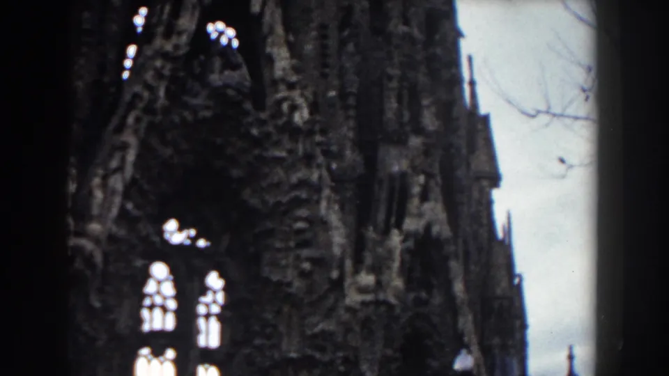 1959 Barcelona church architecture with elaborate Gothic-style masonry, bright arched windows, and a dark vertical film or structural edge.