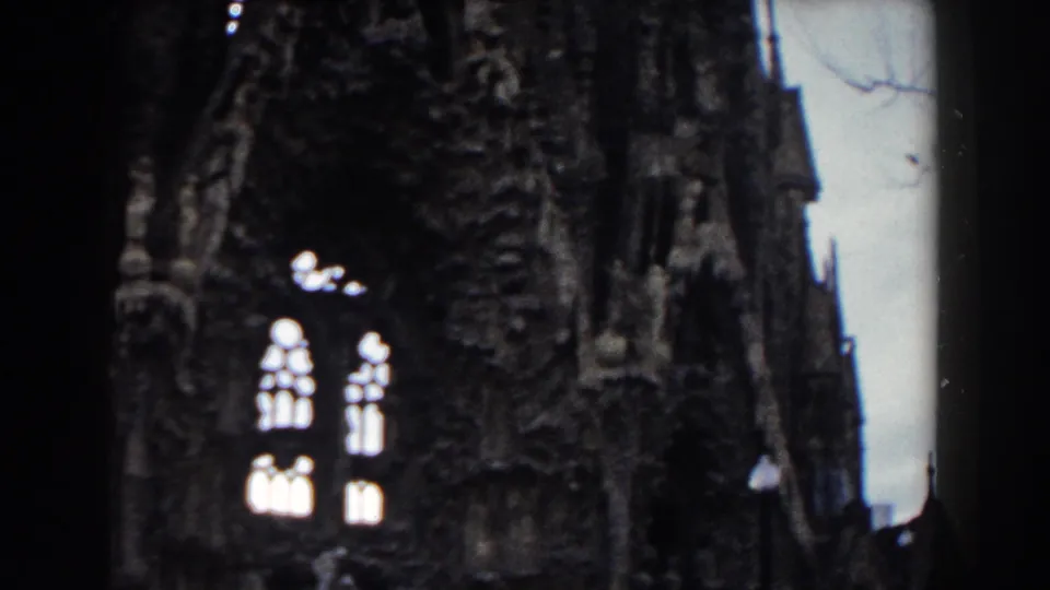 Visitor-shot 1959 Barcelona church detail showing paired arched windows, dense carved masonry, and soft exposure from 8mm film.