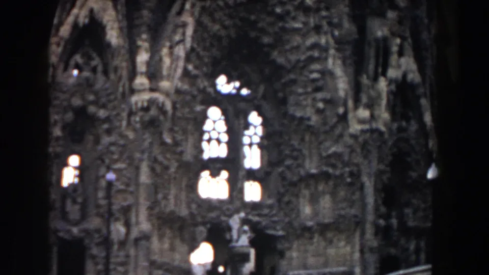 1959 Barcelona church facade detail with carved Gothic-style ornament, glowing arched windows, columns, and a small statue-like form.