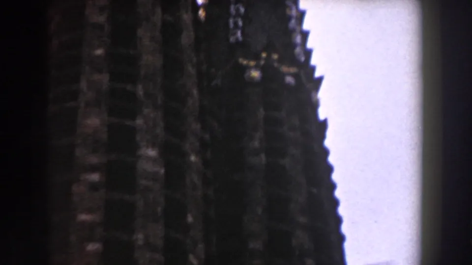 1959 8mm Barcelona footage shows dark, ornate cathedral spires rising against a pale sky in a close upward view.