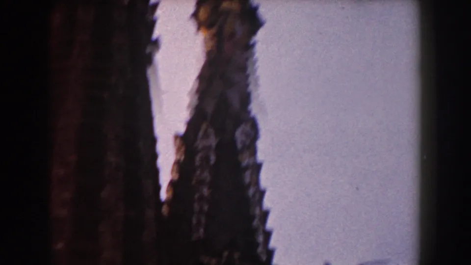 A handheld 8mm view in Barcelona frames narrow cathedral spires and decorative finials against a bright, washed sky.