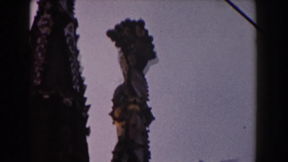 The 1959 home-movie pan looks upward at two ornate Barcelona cathedral spires, with their edges silhouetted against open sky.