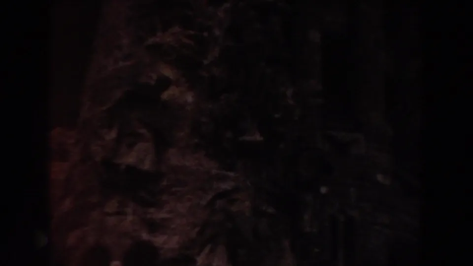 Close 1959 Barcelona 8mm view of dark weathered stone carving inside a historic interior, with most detail held in shadow.