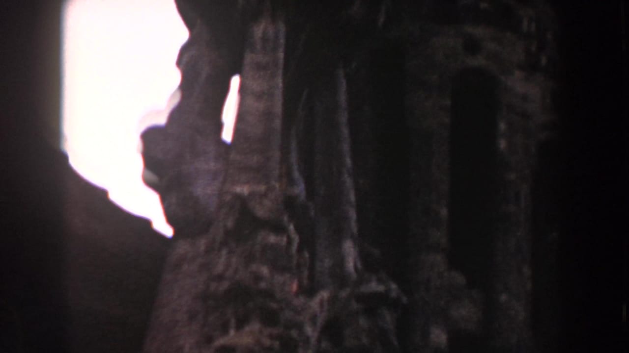 Carved stone form silhouetted beside a bright opening or window.