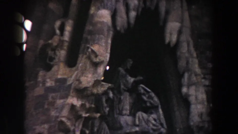 1959 Barcelona 8mm frame showing a dim stone figure and carved architectural interior near bright decorative window openings.