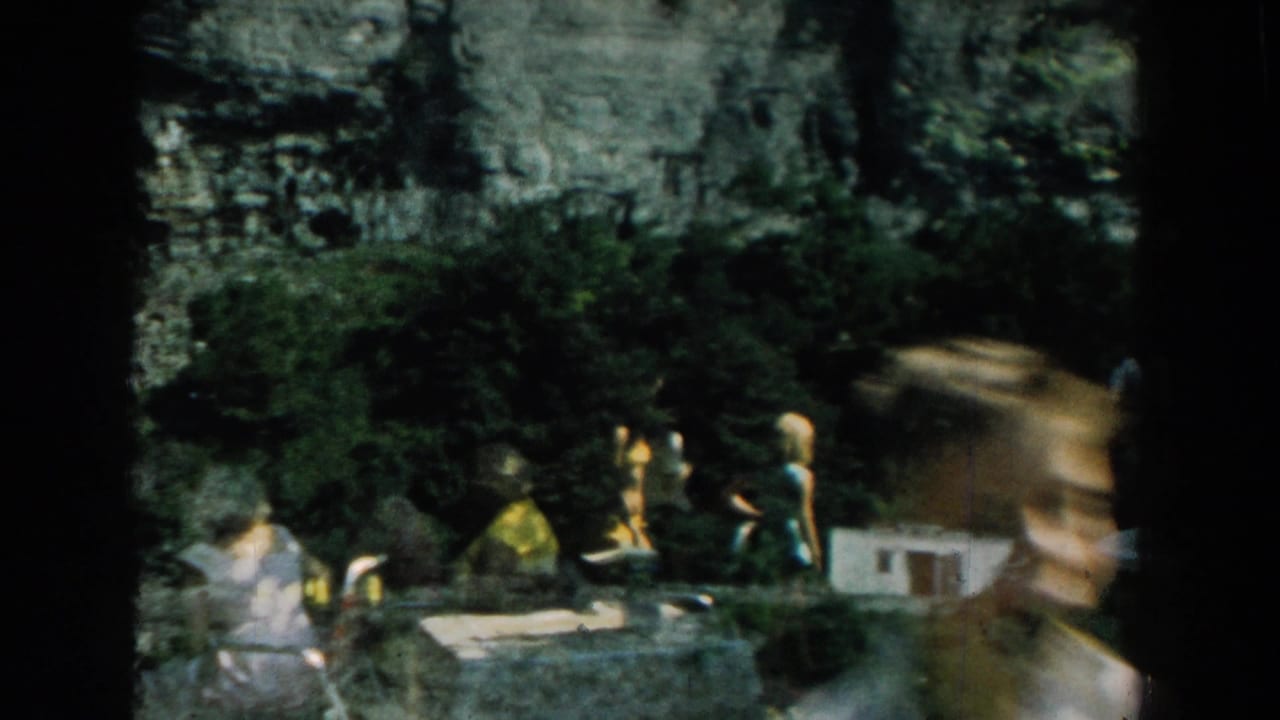 Backyard scene with people near lawn chairs and dark film edges.