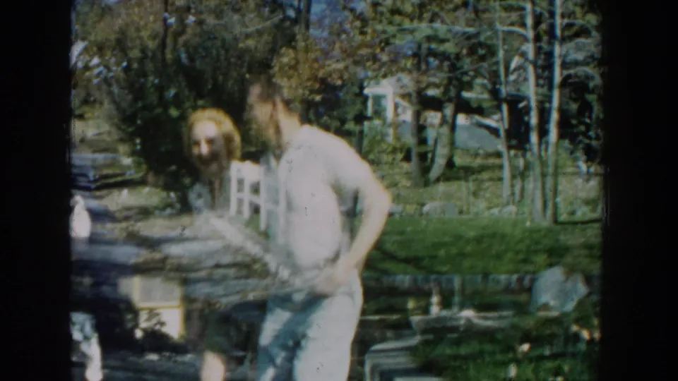 The couple turns together in a Michigan backyard, with trees, fencing, and lawn furniture behind them.