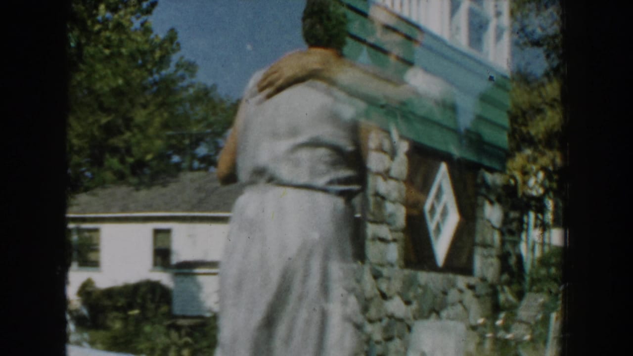 Couple seen from behind while dancing near stone siding and a lawn.