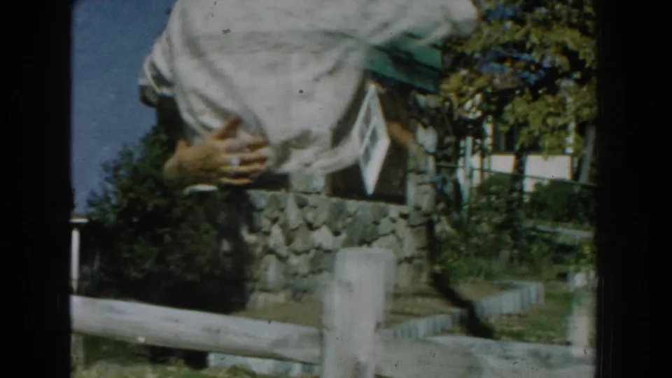 A closer, partially cropped 8mm frame shows the couple embracing as they continue dancing near the house and yard.