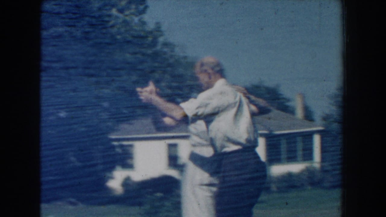 Man and woman dancing in profile on grass beside a house.