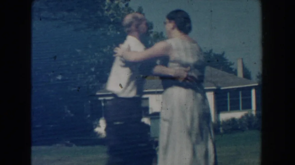 The couple turns together in a Michigan backyard, with a modest house and trees visible behind them.