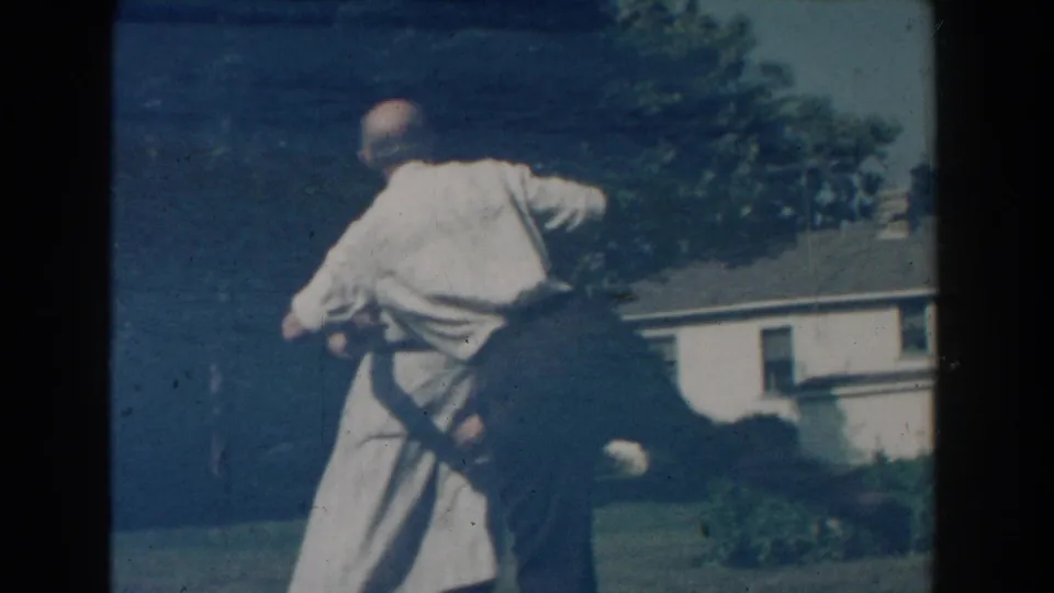 Near the end of the clip, the man leans forward during the dance as the woman remains beside him in the yard.