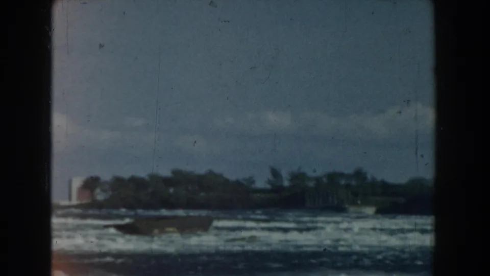 1959 Michigan 8mm view of choppy water, a low wooded shore, distant shoreline forms, and visible film wear.